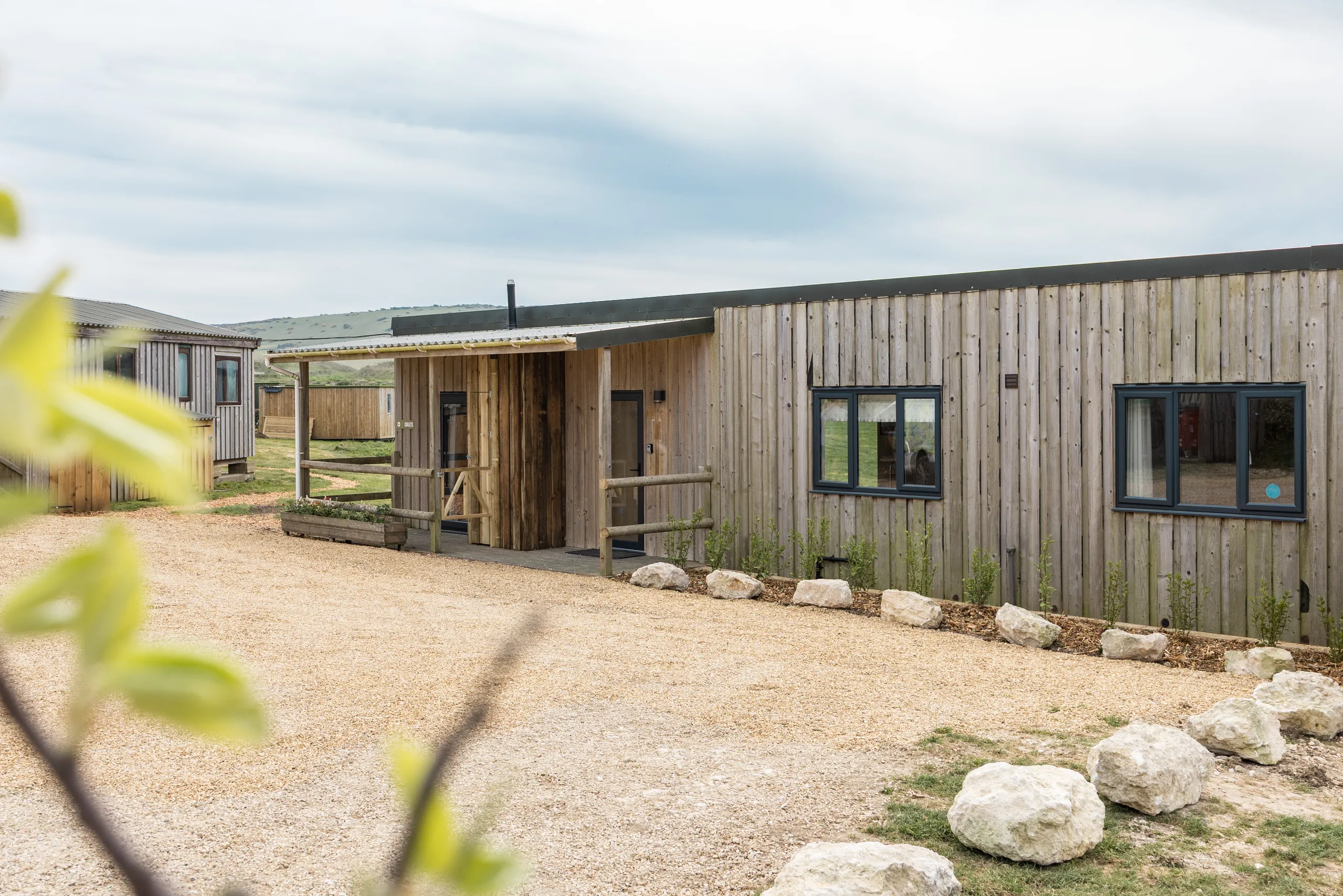 Exterior of a modern timber-clad lodge with gravel driveway and countryside views