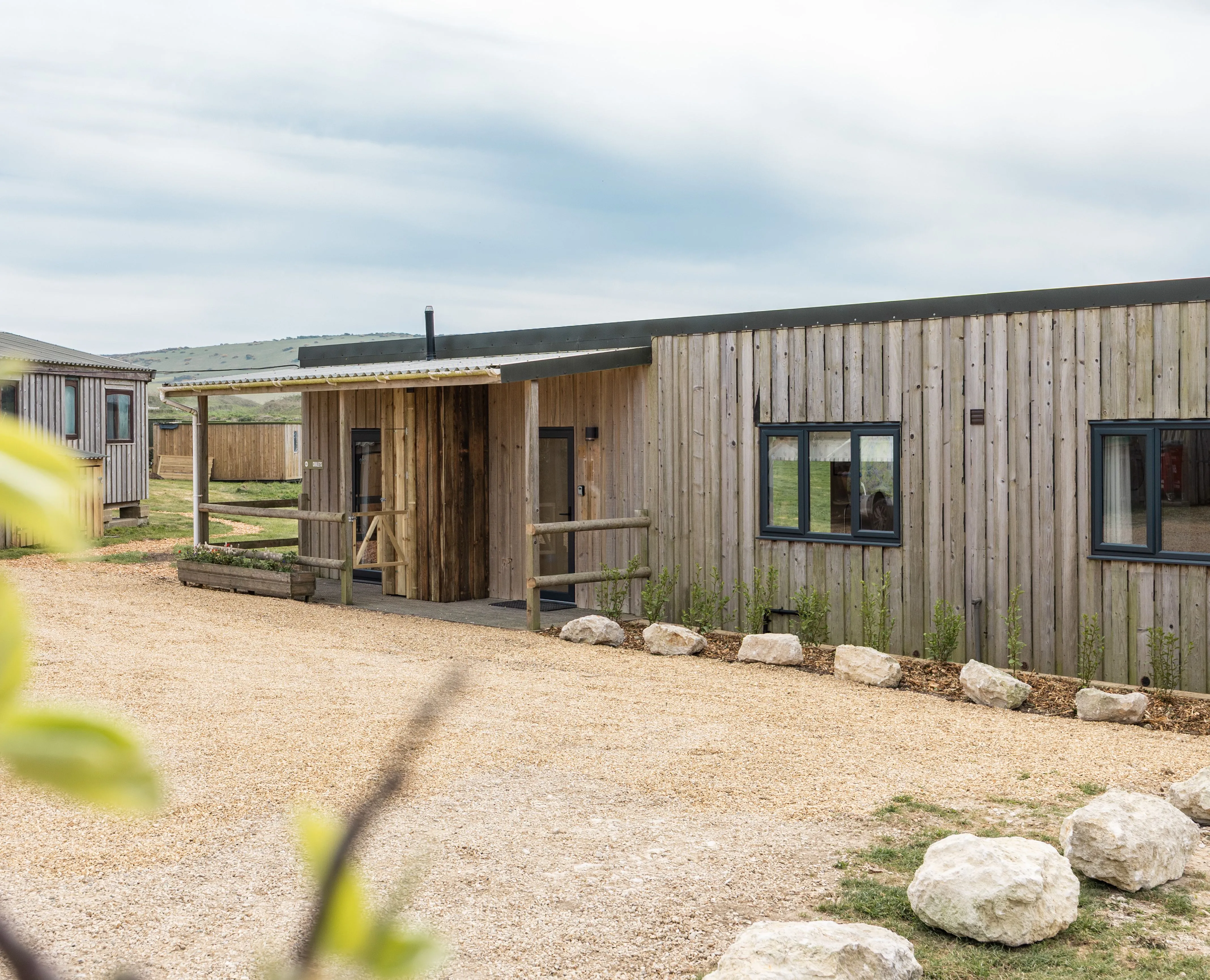 Exterior of a modern timber-clad lodge with gravel driveway and countryside views