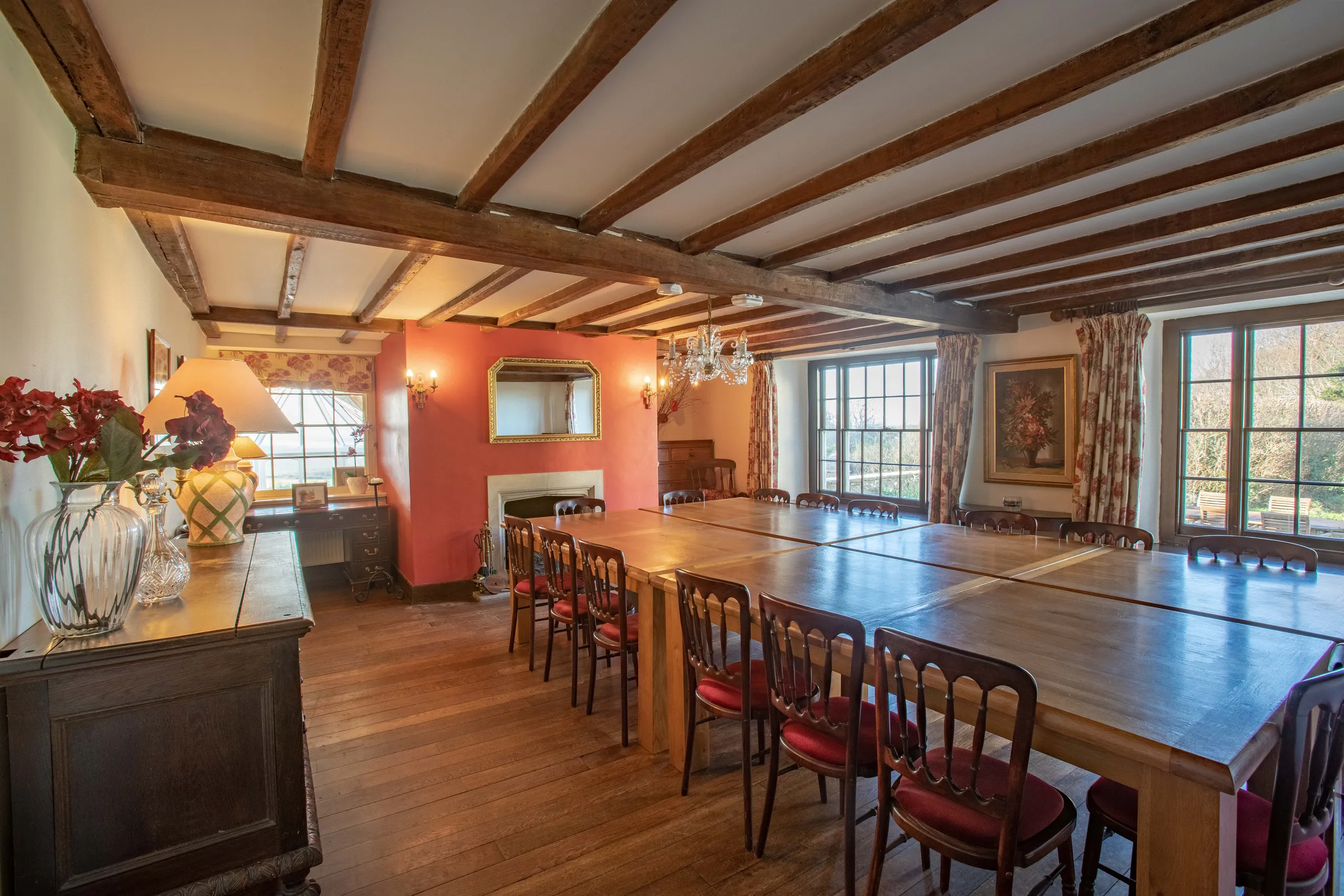 Rustic dining room with long wooden tables, exposed beams and large windows