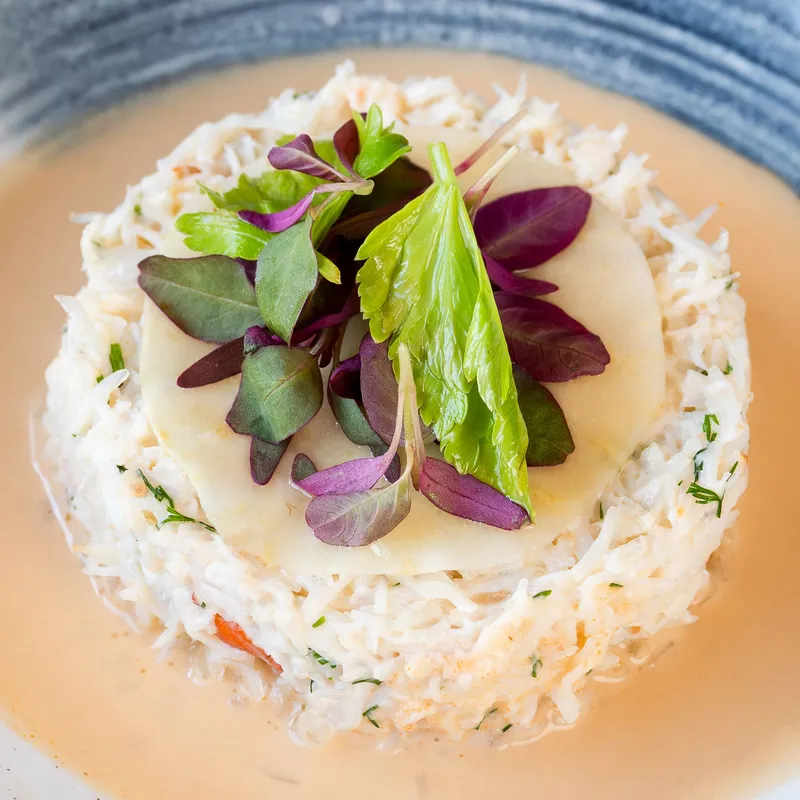 Creamy shredded crab salad topped with microgreens and celery leaves on a plate