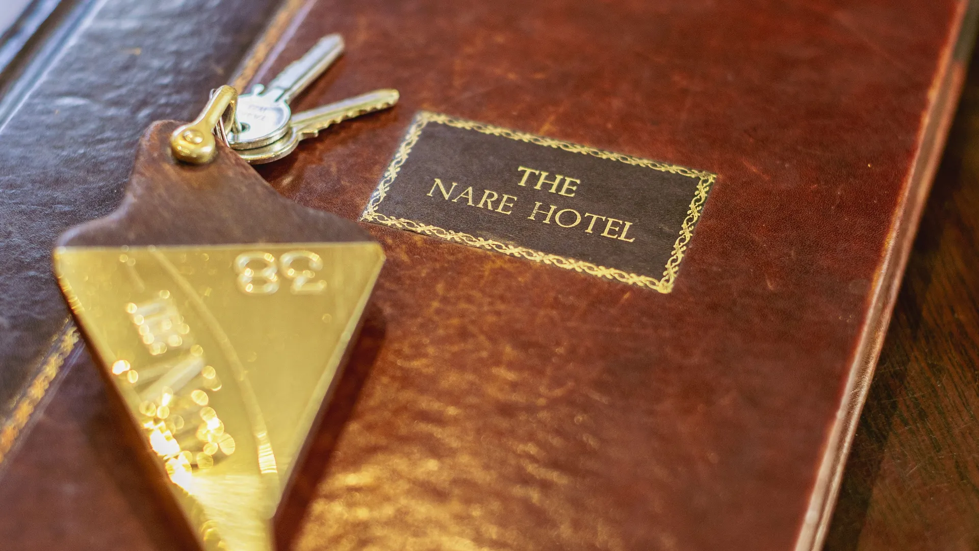 Hotel room keys and a brass room-number fob resting on a leather folder labelled The Nare Hotel