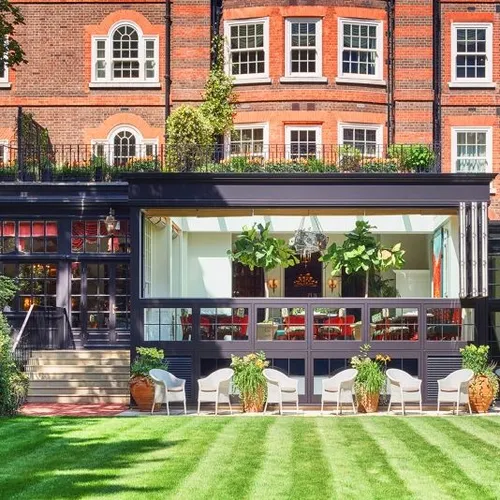 Red-brick hotel overlooking a striped lawn and outdoor seating