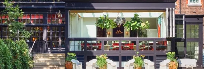 Red-brick hotel overlooking a striped lawn and outdoor seating