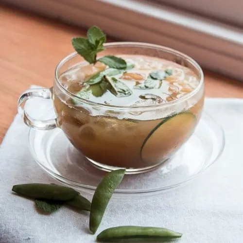 Iced summer cocktail with mint and cucumber in a glass cup on a white napkin