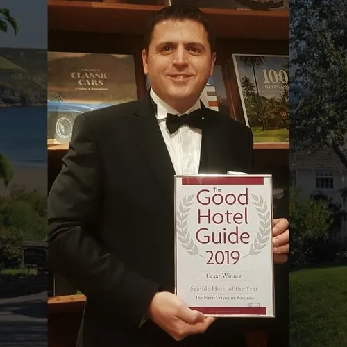 Man in a black tuxedo holding The Good Hotel Guide 2019 Seaside Hotel of the Year award for The Nare