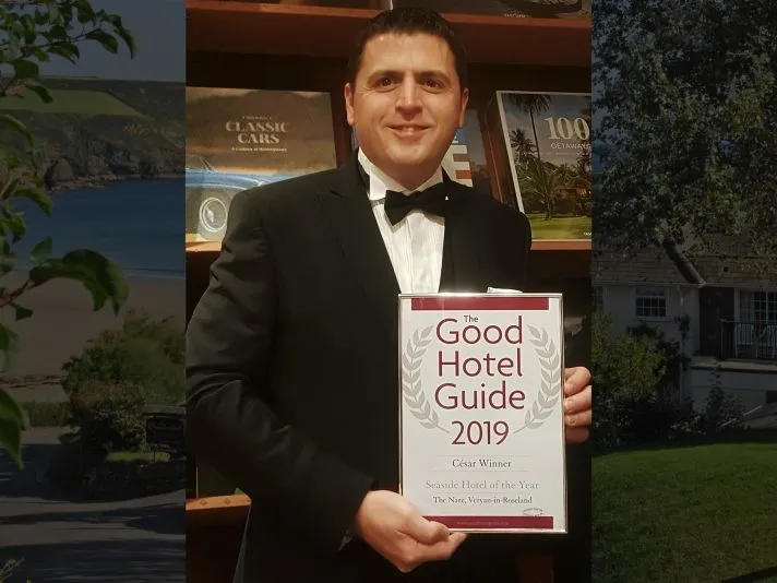 Man in a black tuxedo holding The Good Hotel Guide 2019 Seaside Hotel of the Year award for The Nare