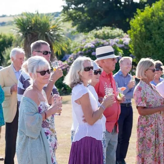 Guests holding drinks at an outdoor garden gathering in the sunshine