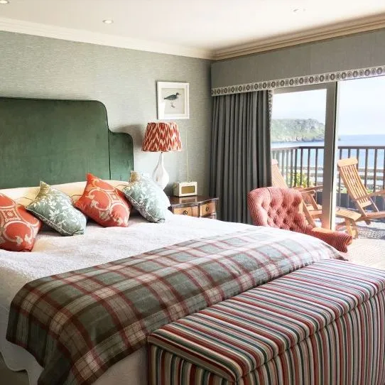 Hotel bedroom with a large bed, patterned cushions and a balcony overlooking the sea