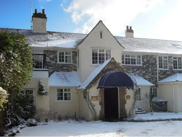 Snow-covered country house with a blue entrance canopy and stone façade