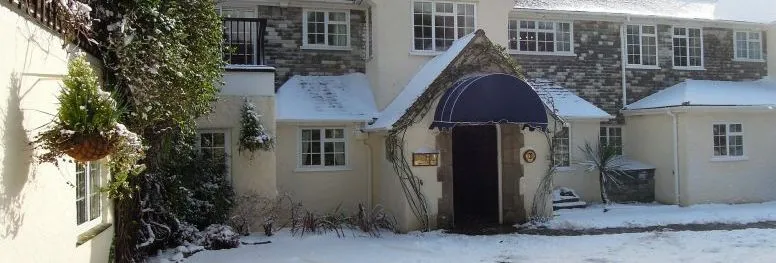 Snow-covered country house with a blue entrance canopy and stone façade
