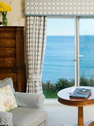 Elegant room with an armchair, antique wooden furniture and a large window overlooking the sea