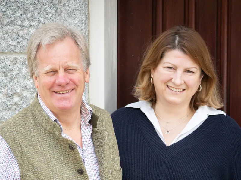 Smiling man and woman standing together outside a stone building