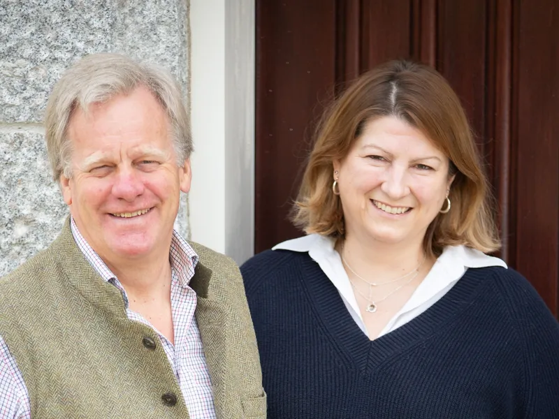 Smiling man and woman standing together outside a stone building