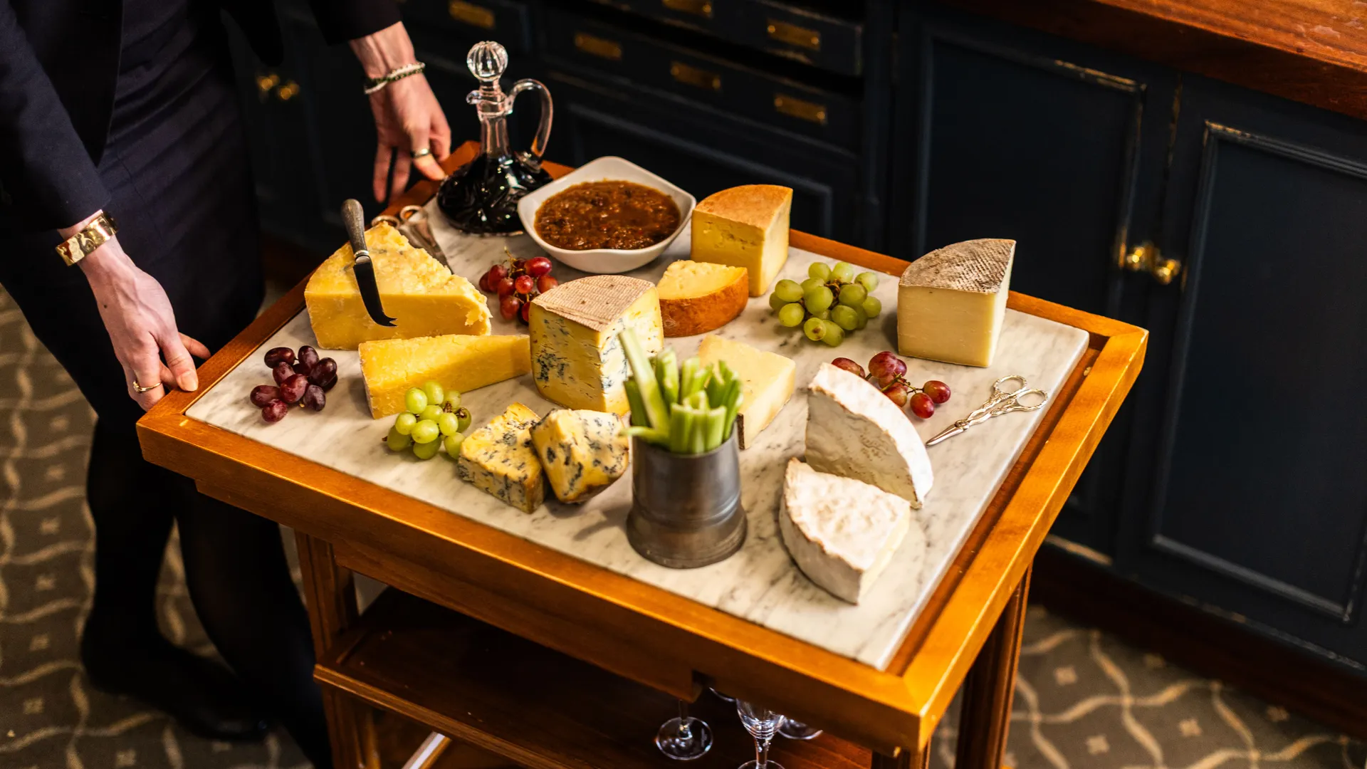 Cheese trolley with assorted cheeses, grapes, celery and chutney in a dining room