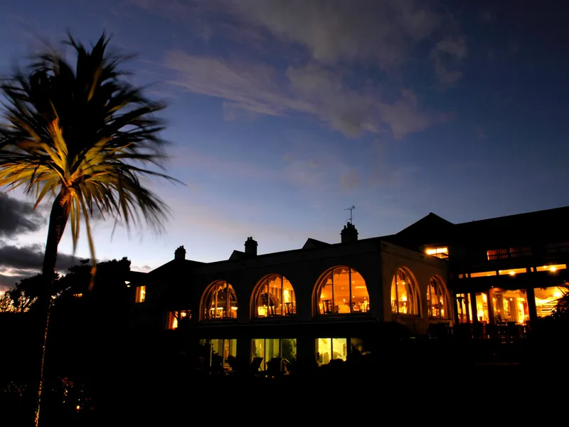 Palm tree beside a warmly lit hotel building at dusk