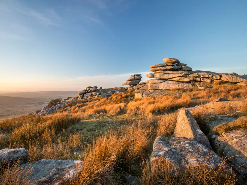 Bodmin Moor Golden light over rugged granite tors and moorland grass under a clear blue sky
