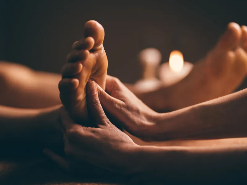Close-up of a therapist giving a relaxing foot massage in a dimly lit spa setting.
