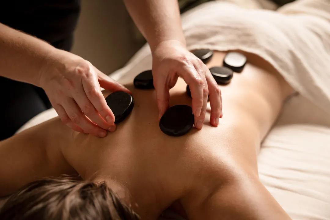 Therapist placing hot stones on a person's back during a spa massage treatment