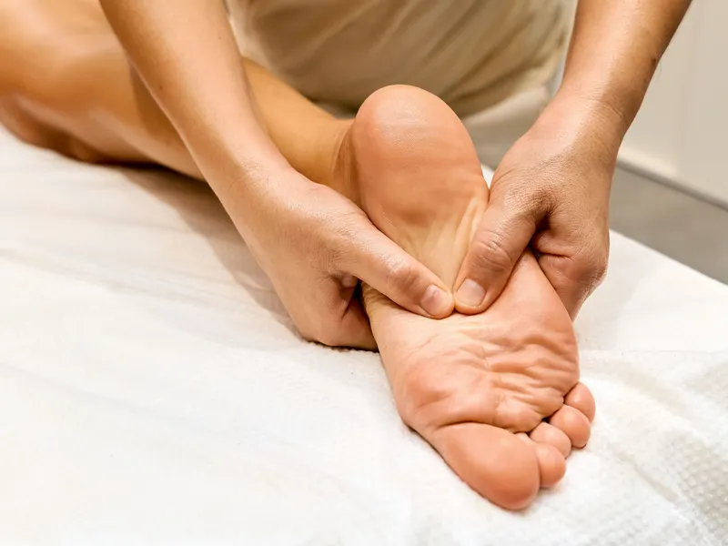 Close-up of a person receiving a foot massage on a treatment bed.