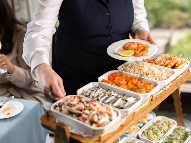 Server presenting a seafood buffet trolley with prawns, smoked salmon, anchovies and other cold dishes in a restaurant