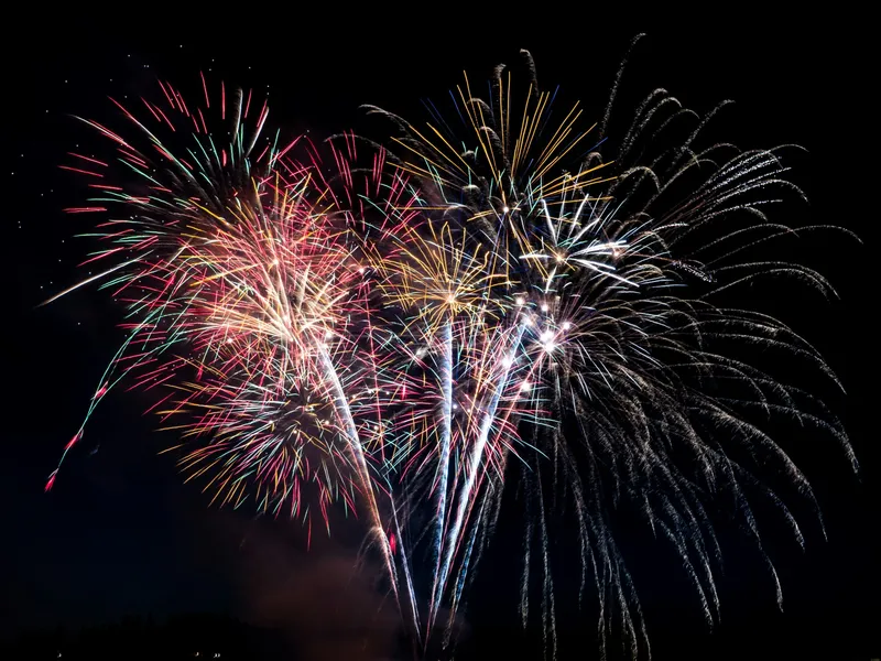 Colourful fireworks bursting across a dark night sky