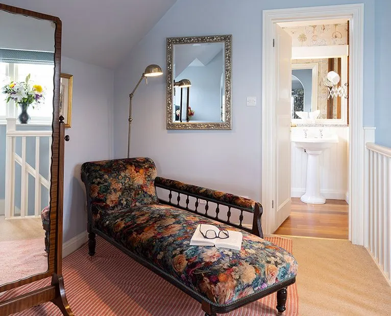 Elegant upper-floor landing with a floral chaise longue, full-length mirror and adjoining bathroom