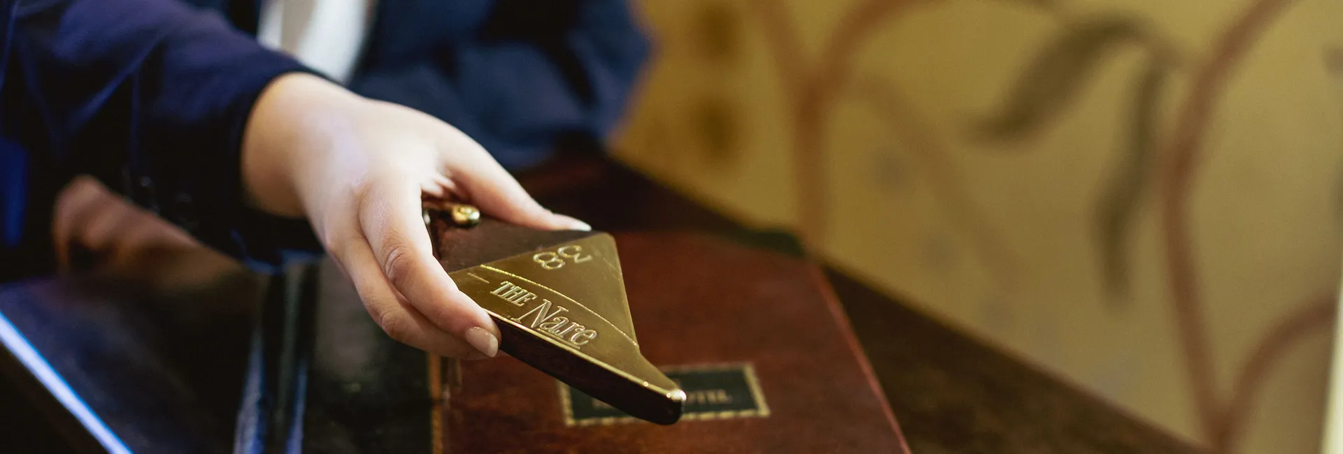 Guest placing room key number 338 on a leather desk at The Nare hotel
