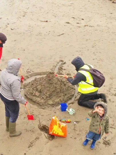 Aerial view of adults and a child building a large sandcastle on a sandy beach