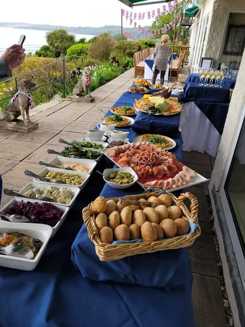 Outdoor buffet spread on a terrace with sea views, Union Jack bunting and champagne glasses.