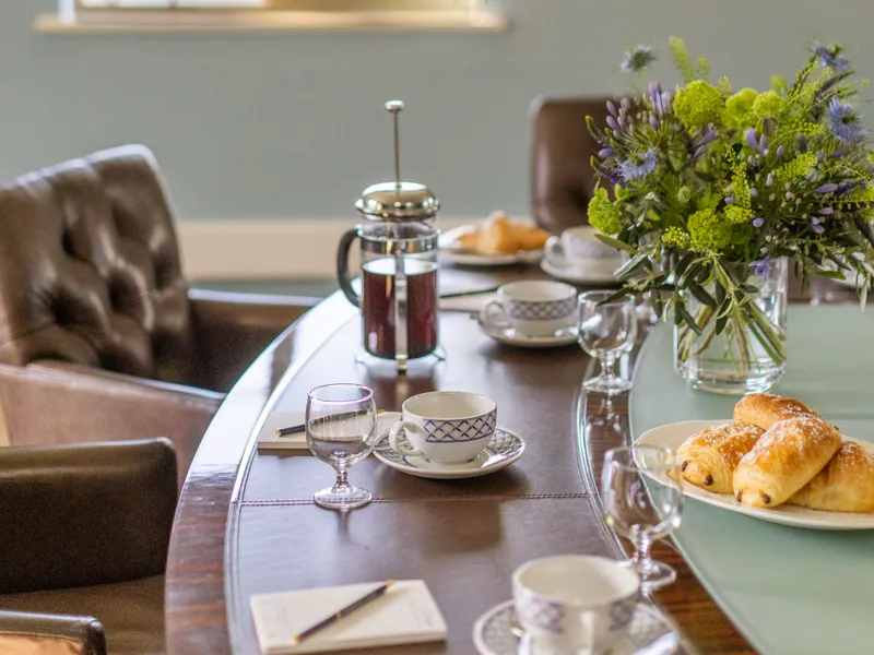 Dining table set with pastries, tea and flowers in a bright, elegant room