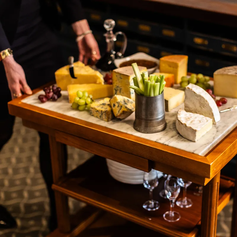 Cheese trolley with assorted artisan cheeses, grapes and celery in an elegant dining room