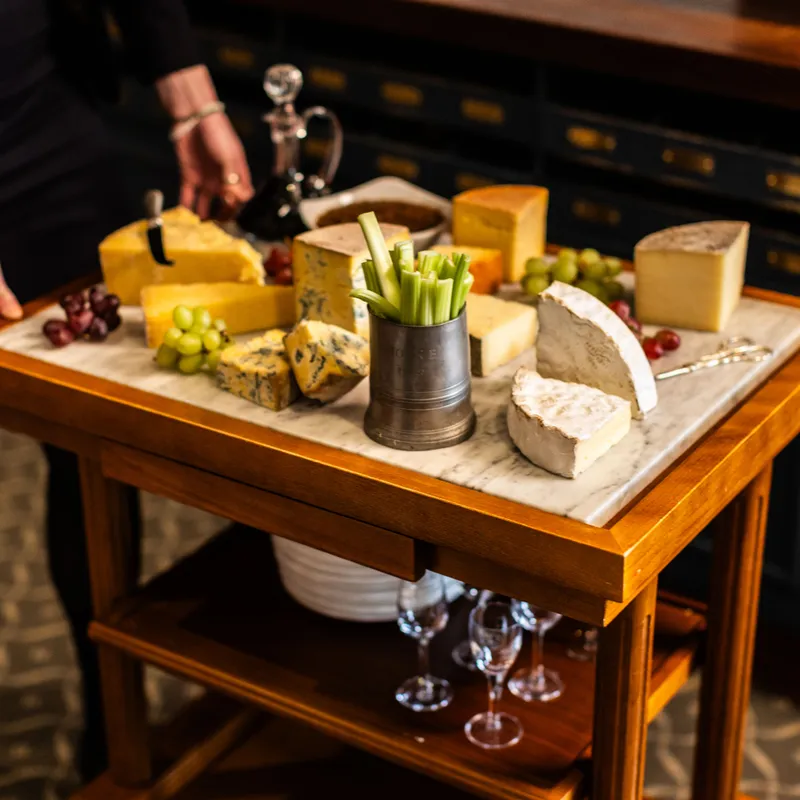 Cheese trolley with assorted artisan cheeses, grapes and celery in an elegant dining room