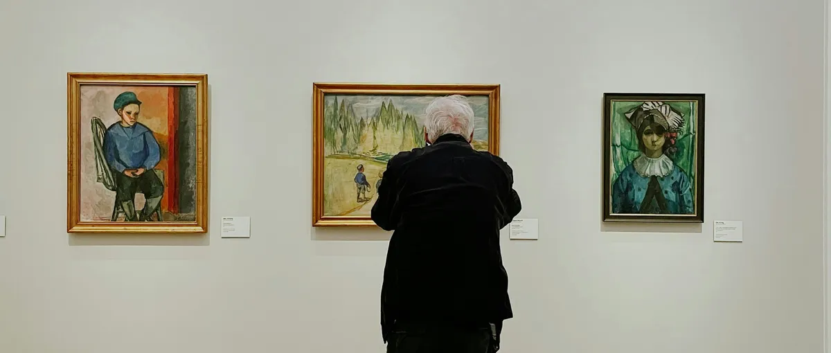 Visitor viewing framed paintings in a quiet art gallery
