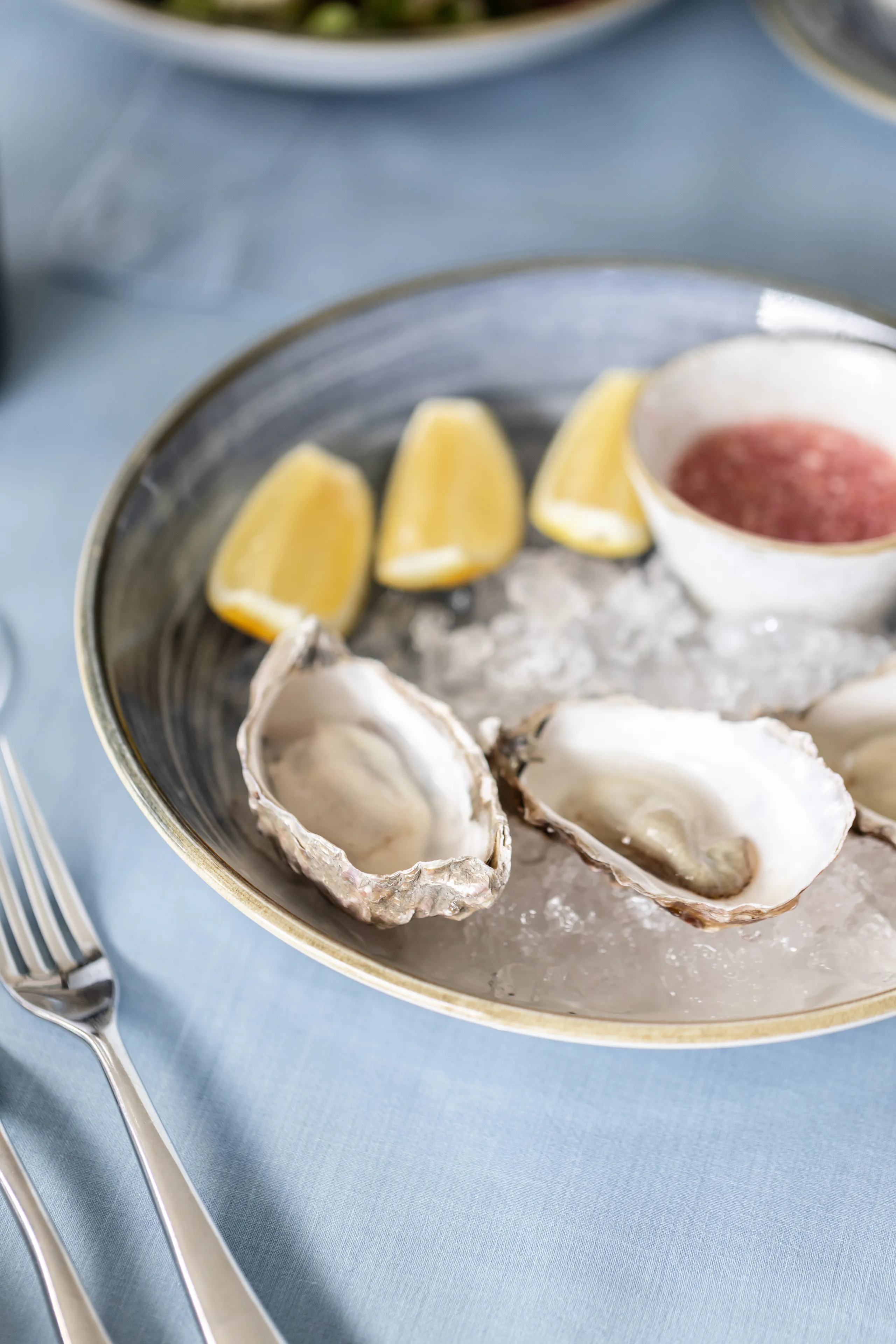 Fresh oysters served on crushed ice with lemon wedges and a small dish of red sauce