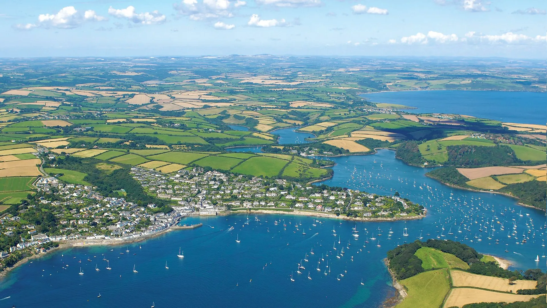 Aerial view of the Roseland Peninsula with blue estuary waters, sailing boats and patchwork fields in Cornwall