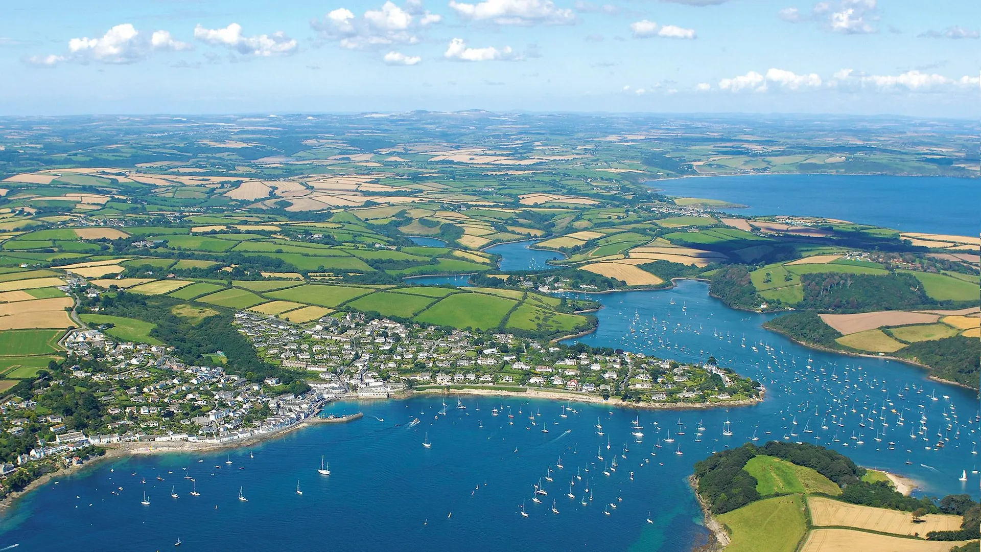 Aerial view of the Roseland Peninsula with blue estuary waters, sailing boats and patchwork fields in Cornwall