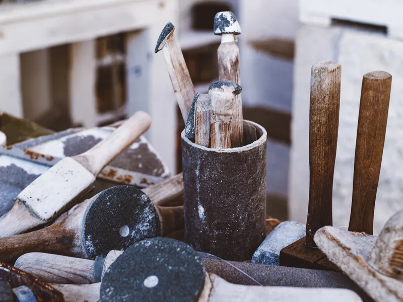 Barbara Hepworth's Close-up of stone-carving and sculpting tools on a dusty workbench in a workshop
