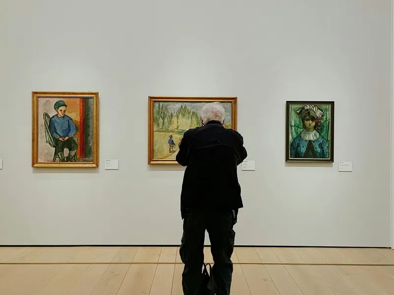 Visitor viewing framed paintings in a quiet art gallery