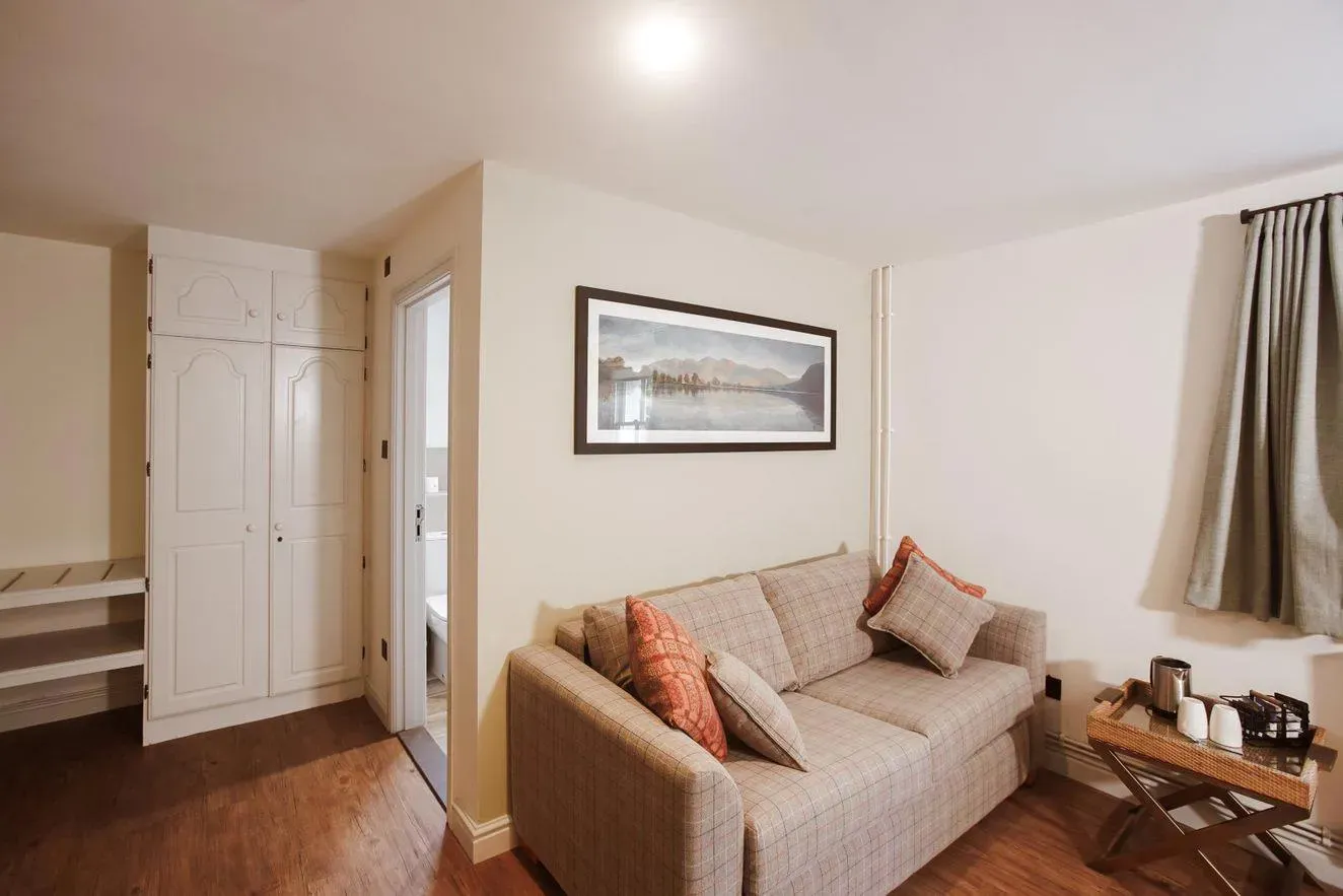 Cosy hotel suite sitting area with a beige sofa, cushions, tea tray and built-in wardrobe.