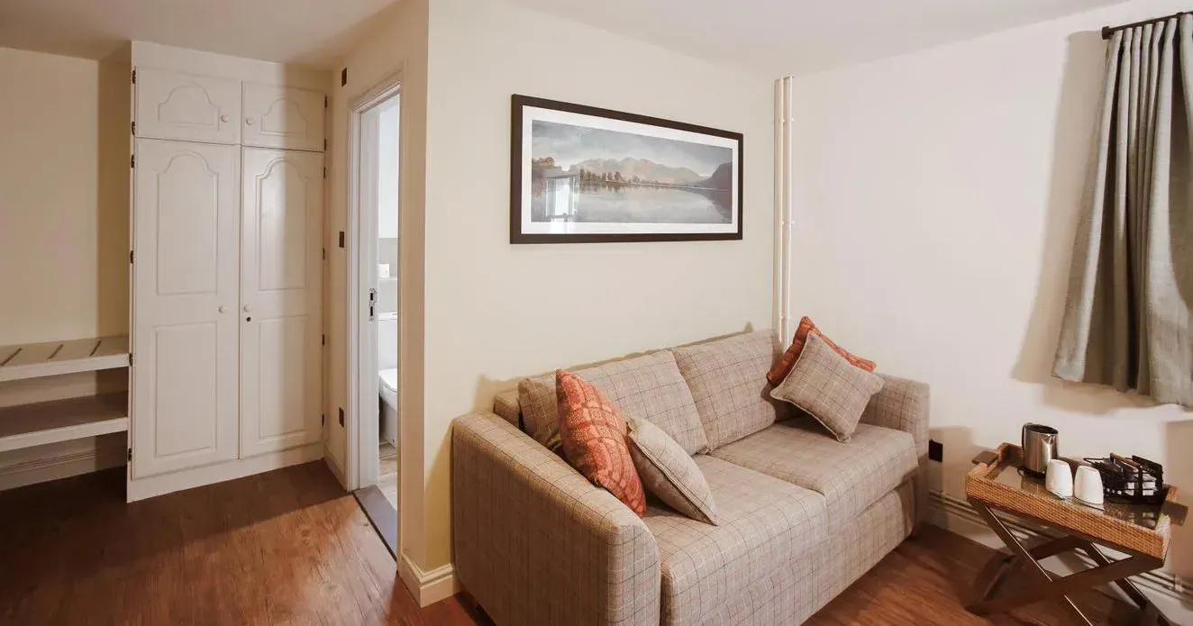 Cosy hotel suite sitting area with a beige sofa, cushions, tea tray and built-in wardrobe.