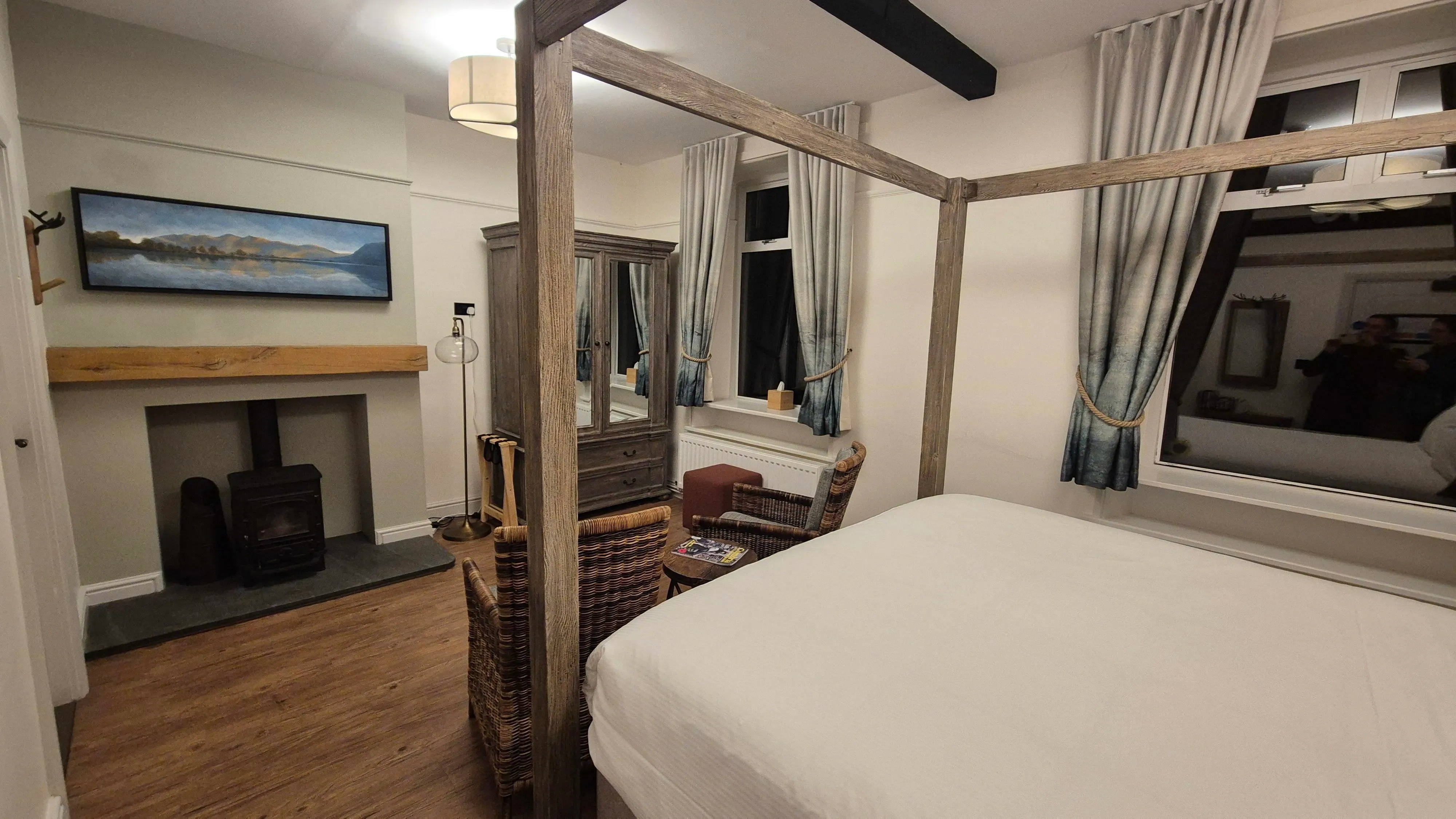 Cosy bedroom with a wooden four-poster bed, wicker chairs and a fireplace
