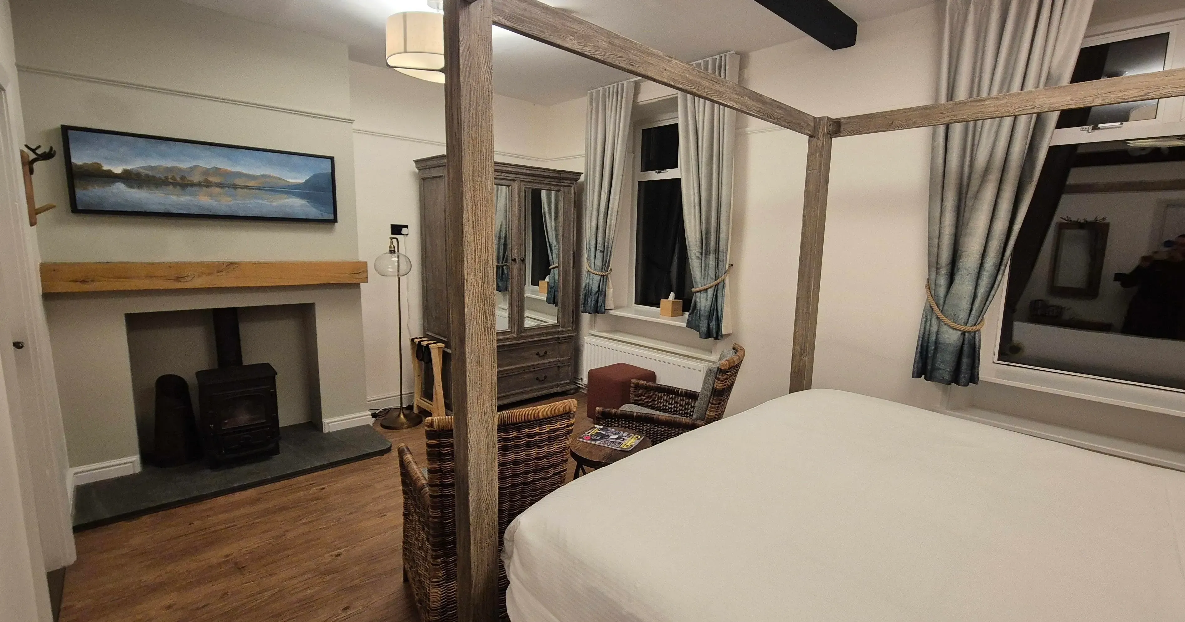 Cosy bedroom with a wooden four-poster bed, wicker chairs and a fireplace