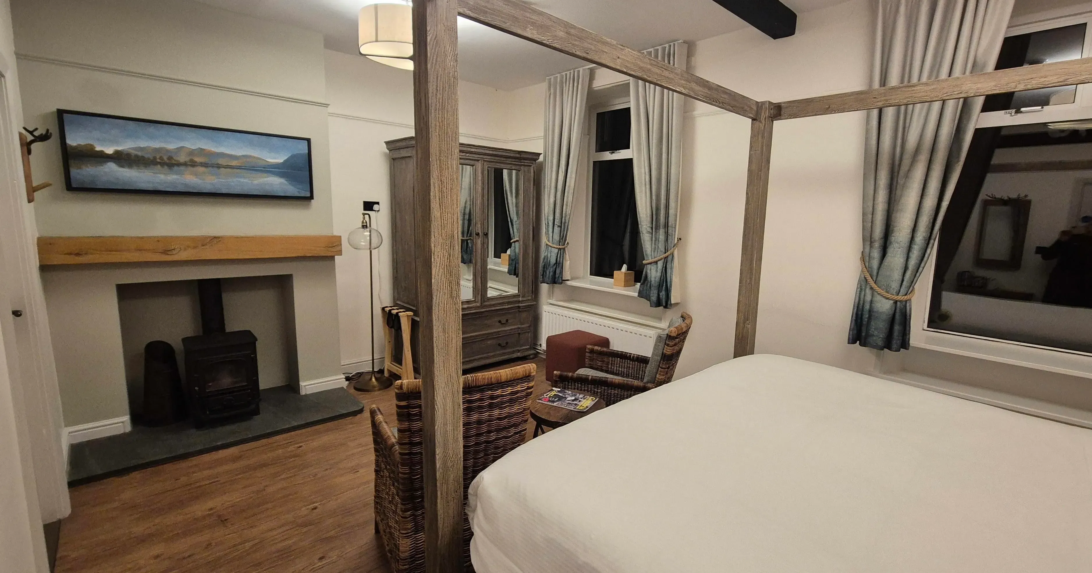 Cosy bedroom with a wooden four-poster bed, wicker chairs and a fireplace