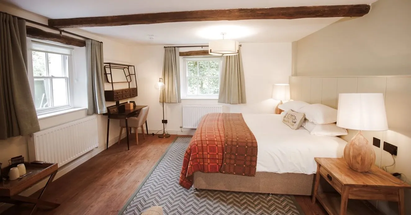 Cosy bedroom with exposed wooden beams, double bed, patterned throw and wooden furniture