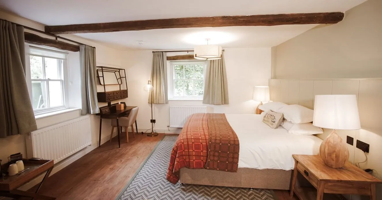Cosy bedroom with exposed wooden beams, double bed, patterned throw and wooden furniture