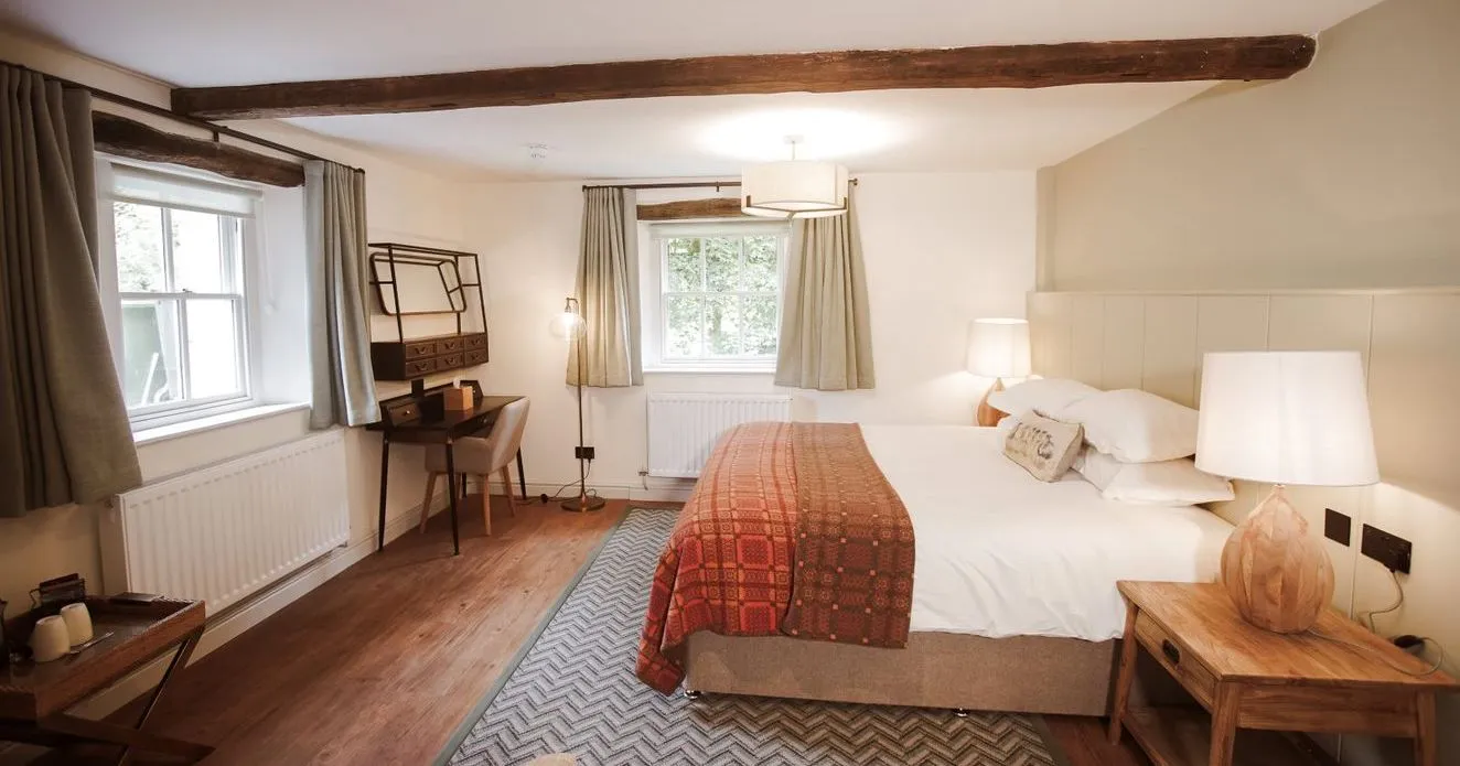 Cosy bedroom with exposed wooden beams, double bed, patterned throw and wooden furniture