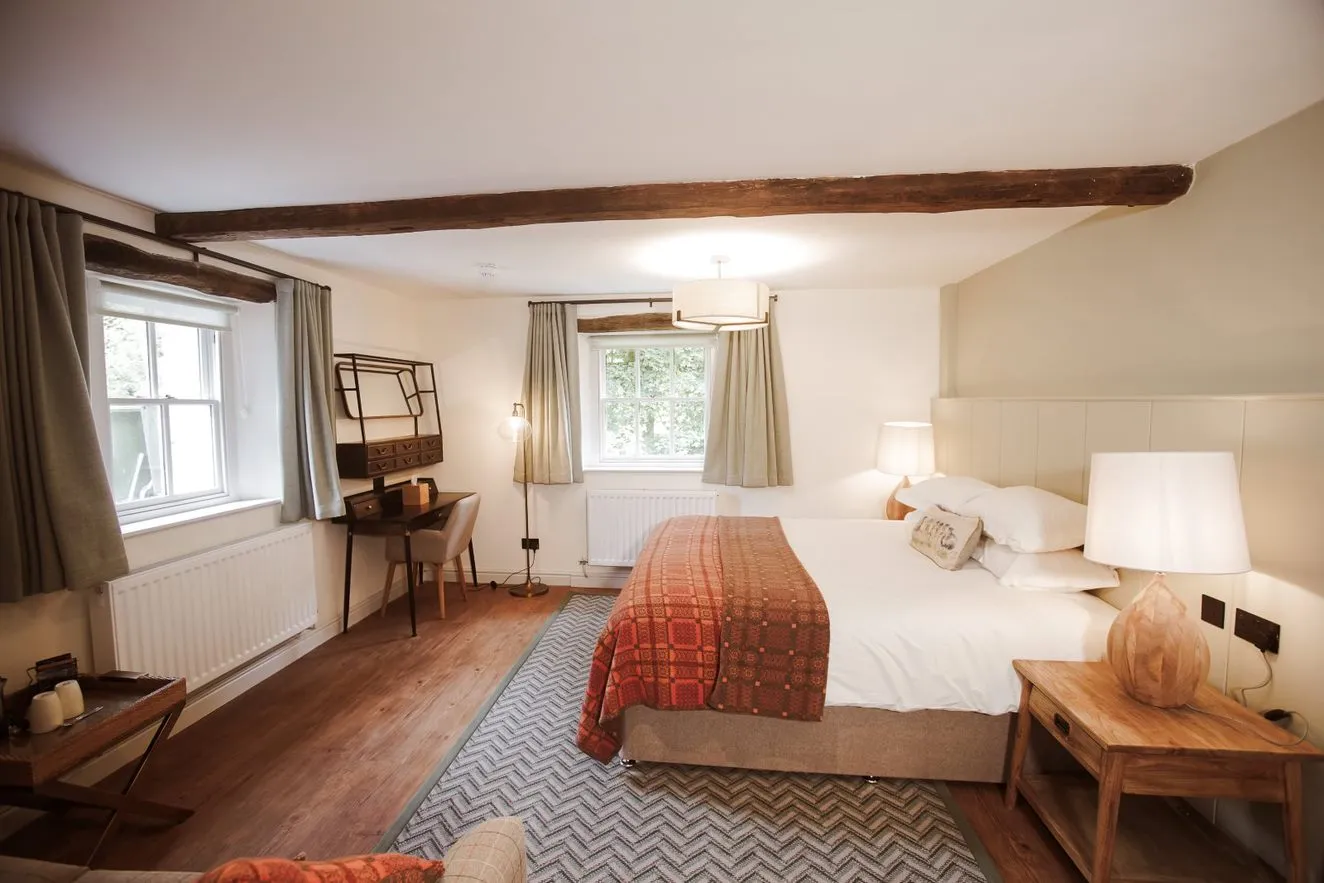 Cosy bedroom with exposed wooden beams, double bed, patterned throw and wooden furniture