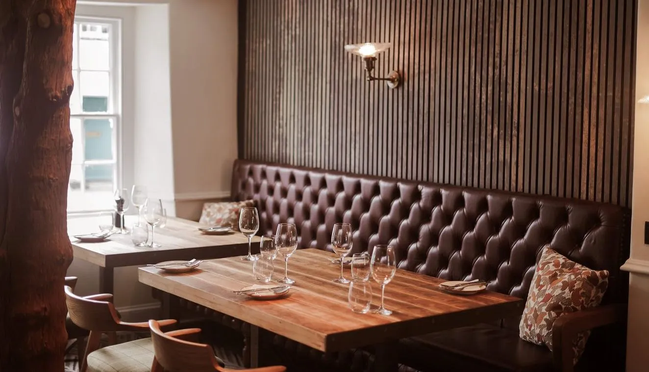 Cosy restaurant dining area with wooden tables, leather banquette seating and striped wall panelling.