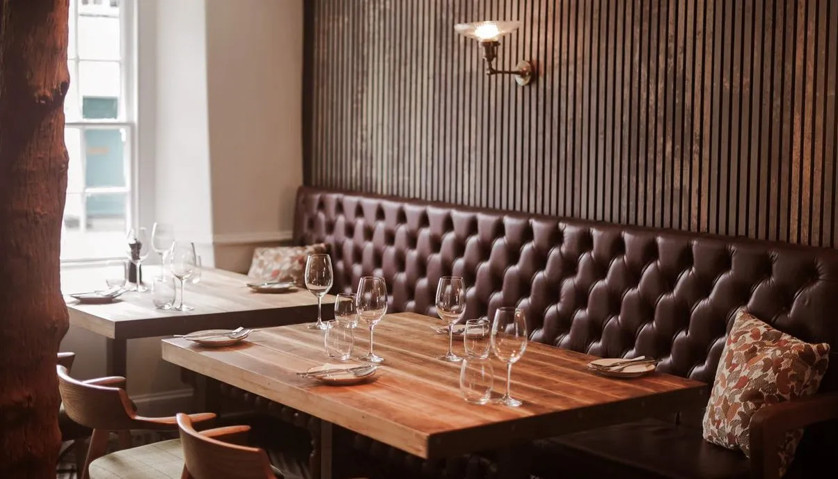 Cosy restaurant dining area with wooden tables, leather banquette seating and striped wall panelling.