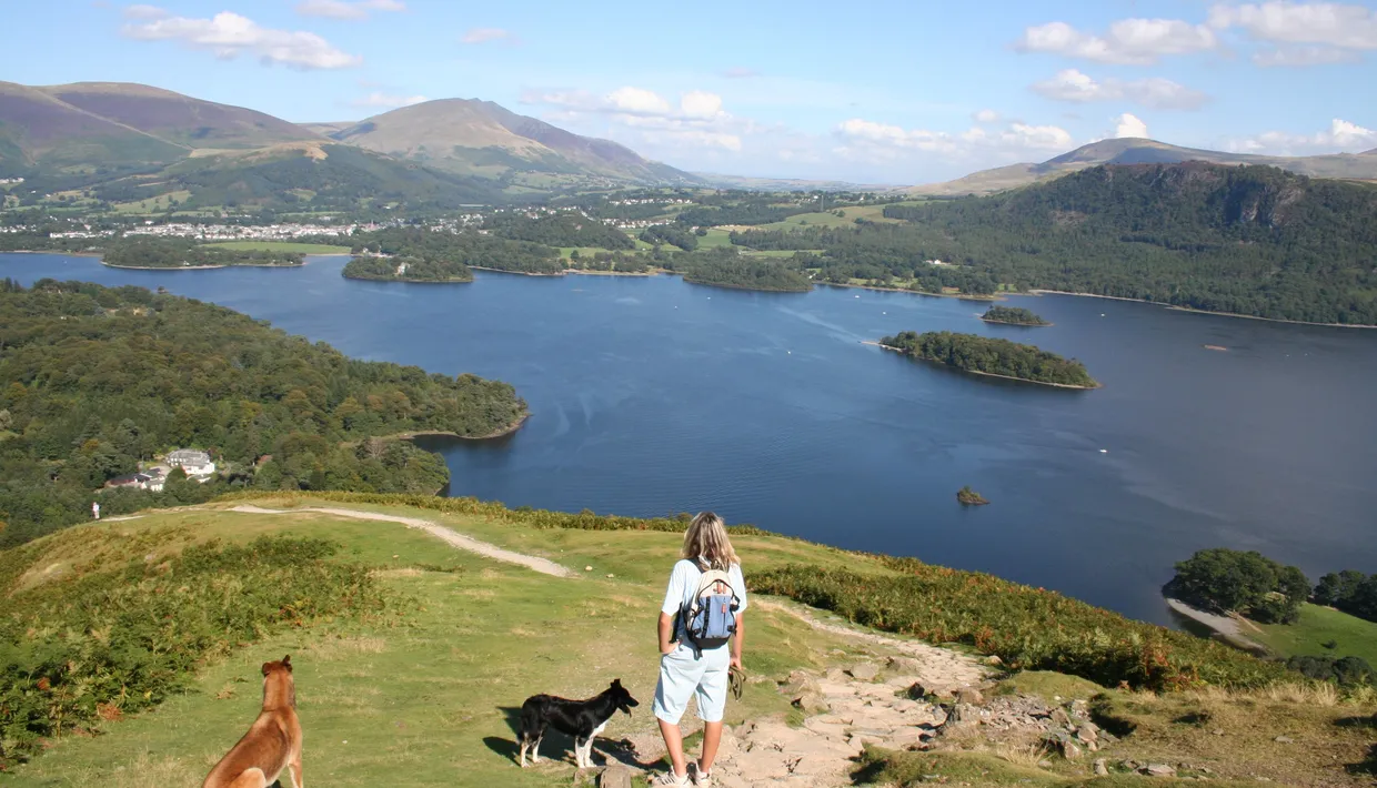 Walker with two dogs overlooking Derwentwater from Catbells in the Lake District